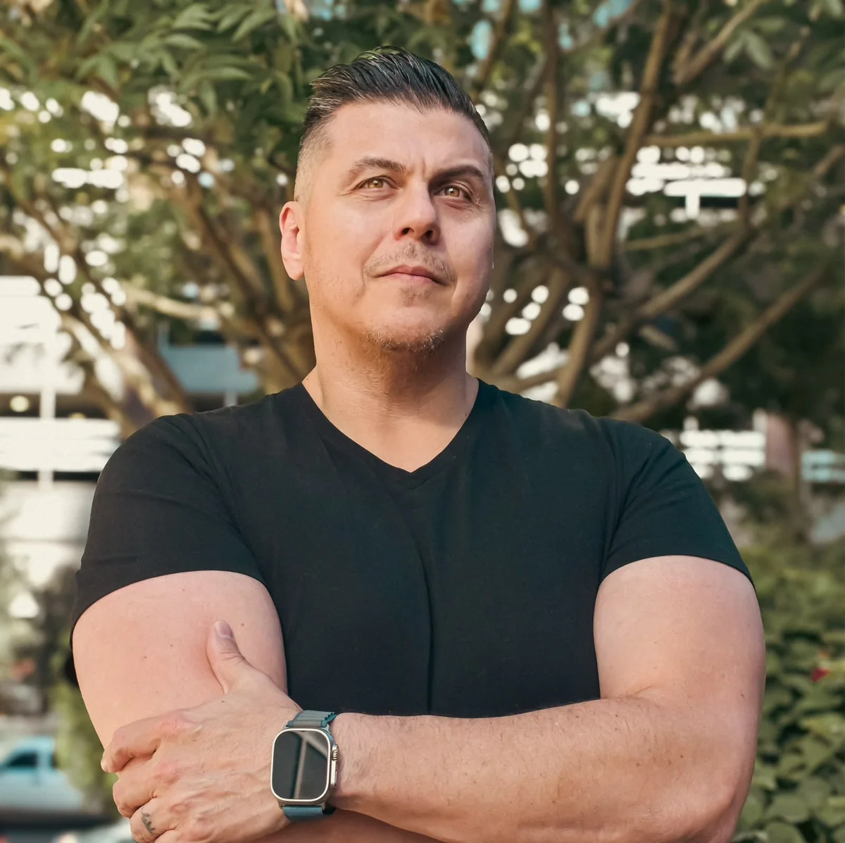 Gabe Kachirisky, arms crossed, under a tree